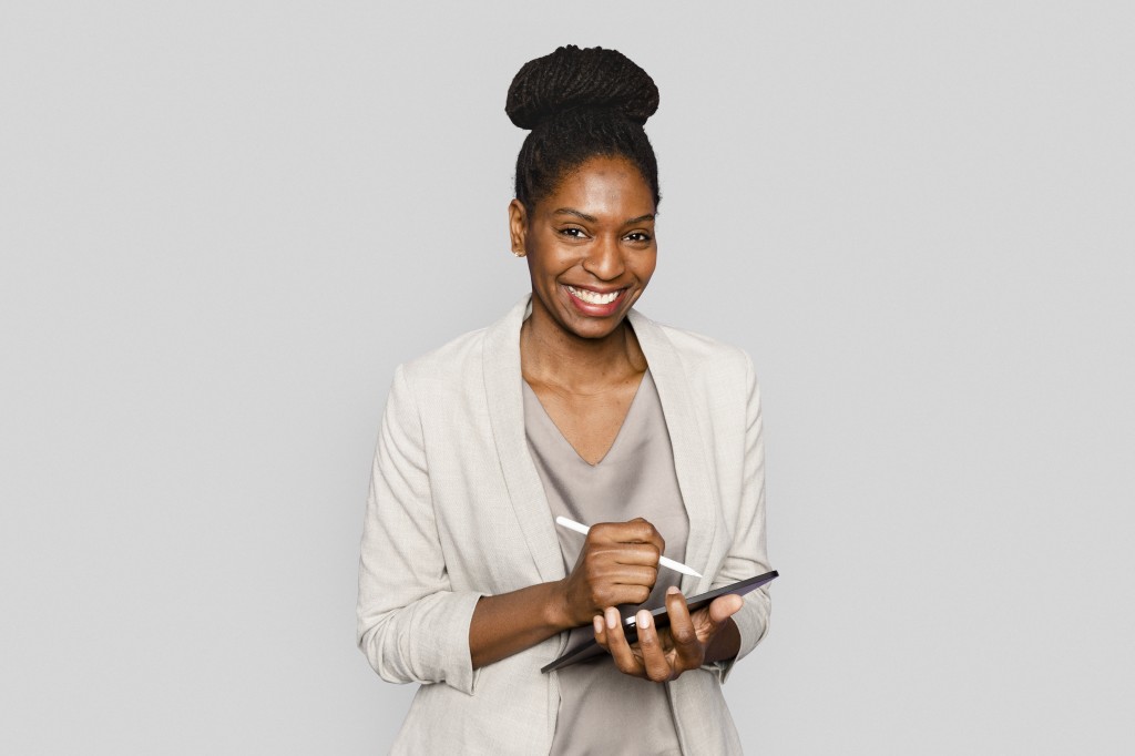 Smiling woman writing notes on tablet digital device