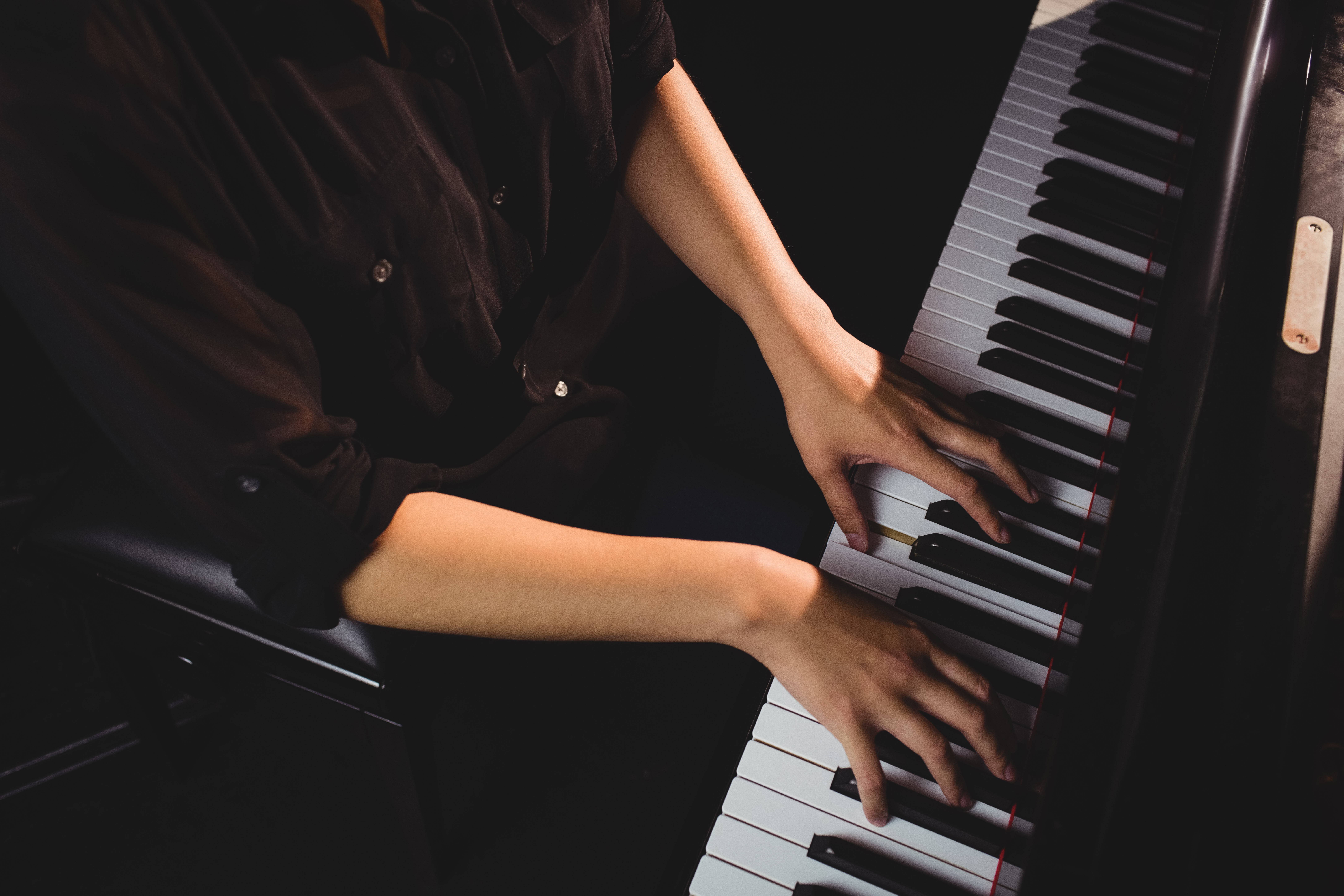 Mid-section of female student playing piano in a studio