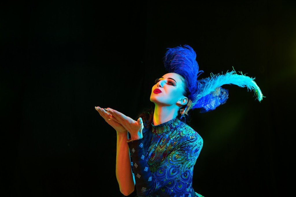 Beautiful young woman in carnival and masquerade costume in colorful neon lights on black background