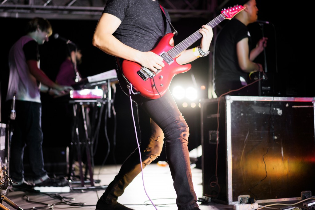 musicians on stage during a concert, guitarist with a red guitar