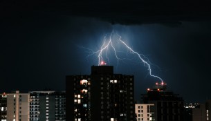 Lightning in the dark sky over the buildings in the city at night