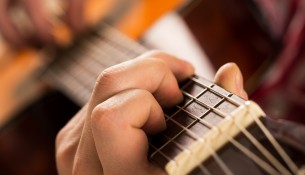Music, close-up. Musician holding a wooden guitar