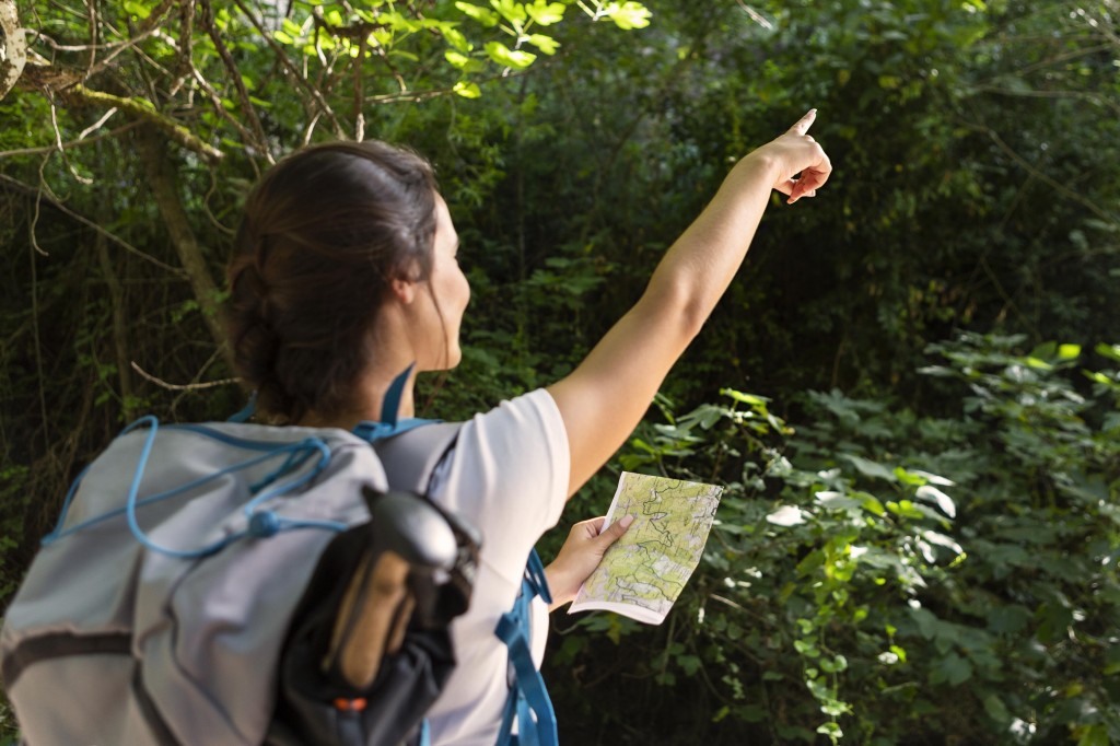 woman-with-backpack-pointing-while-holding-map