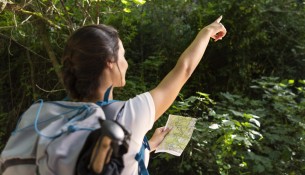 woman-with-backpack-pointing-while-holding-map