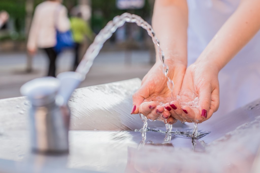 Young woman drinking water from fountain