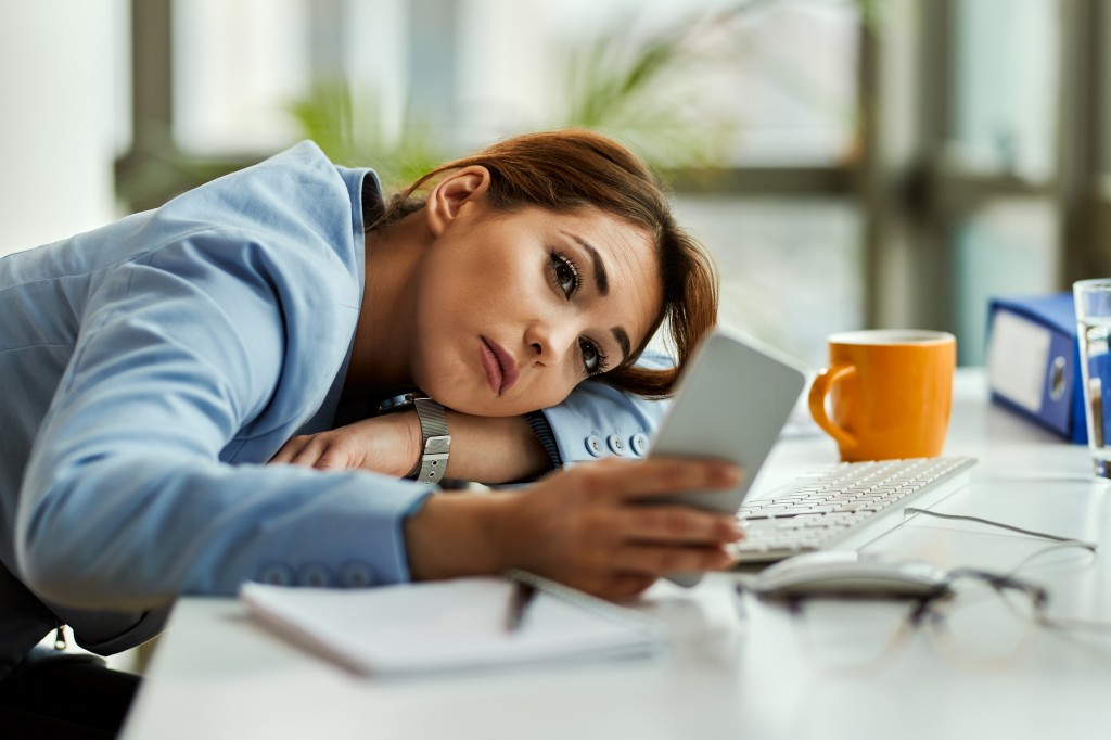 Young businesswoman text messaging on cell phone in the office.