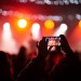 Person close up of recording video with smartphone during a concert.