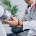 Young male psysician with patient measuring blood pressure