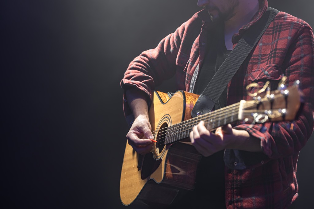 Acoustic guitar in the hands of a guitarist.