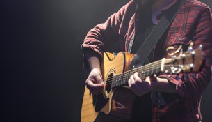 Acoustic guitar in the hands of a guitarist.