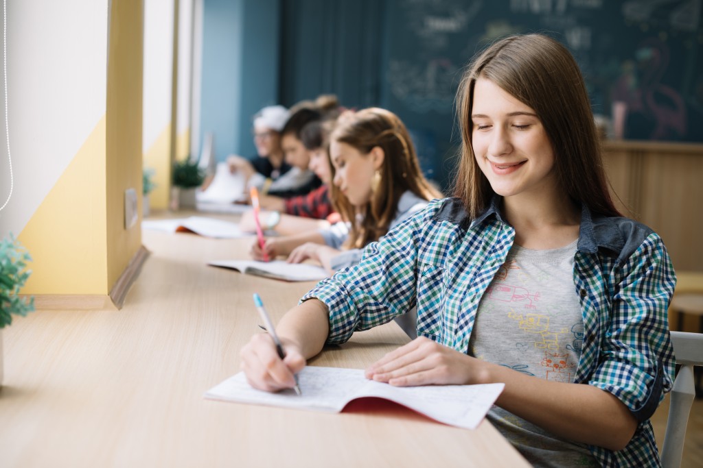 cheerful-teen-preparing-homework