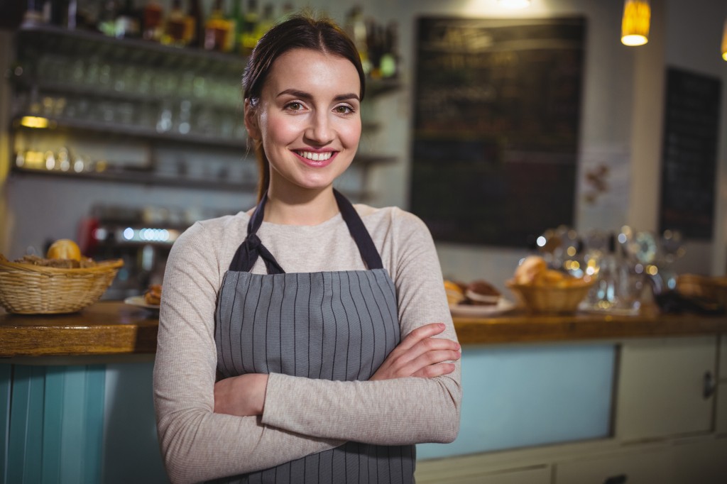 Portrait of smiling waitress standing at counter