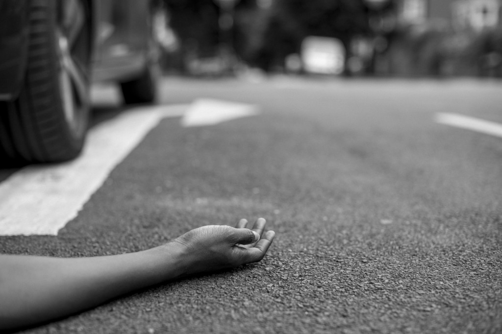 Person lying on the ground after a car accident