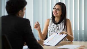 Smiling young businesswoman showing contract to partner