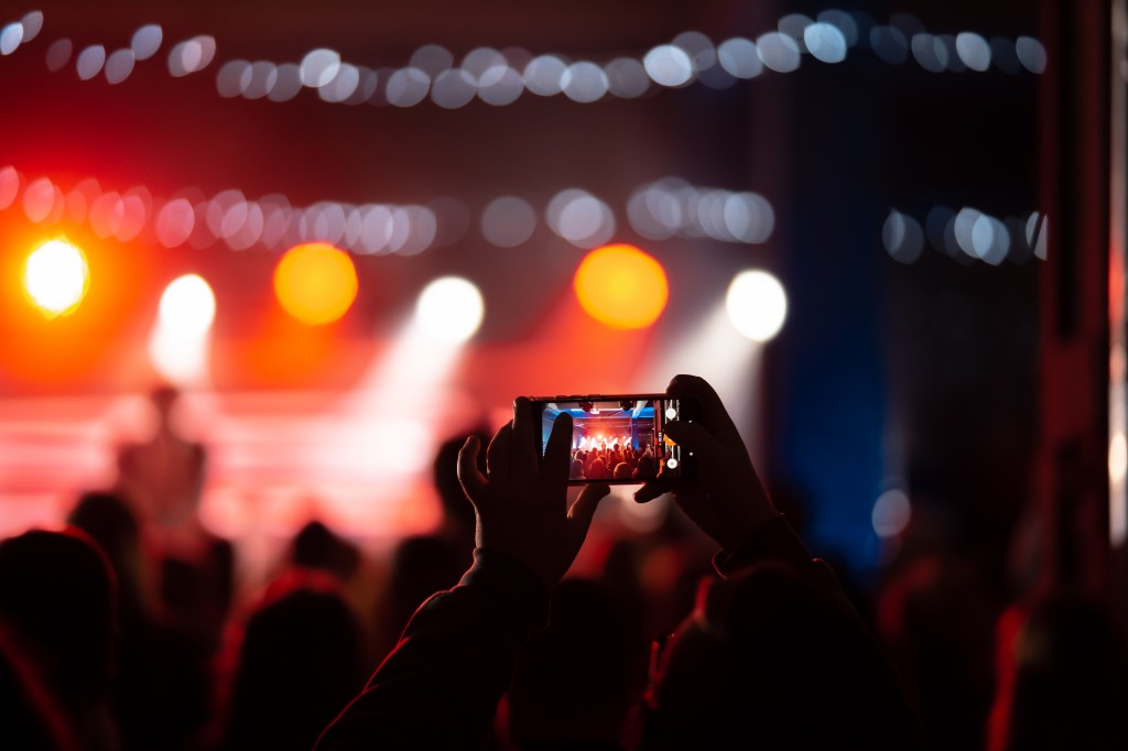 Person close up of recording video with smartphone during a concert.