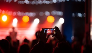 Person close up of recording video with smartphone during a concert.