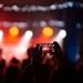 Person close up of recording video with smartphone during a concert.