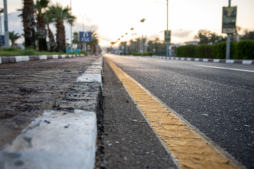 City asphalt road with palm trees along the road at sunset.