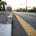 City asphalt road with palm trees along the road at sunset.