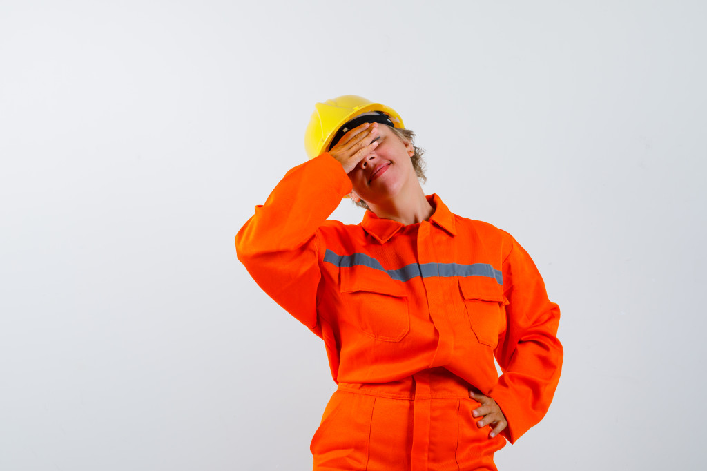 Portrait of mature firewoman holding hand on eyes in uniform and looking tired front view