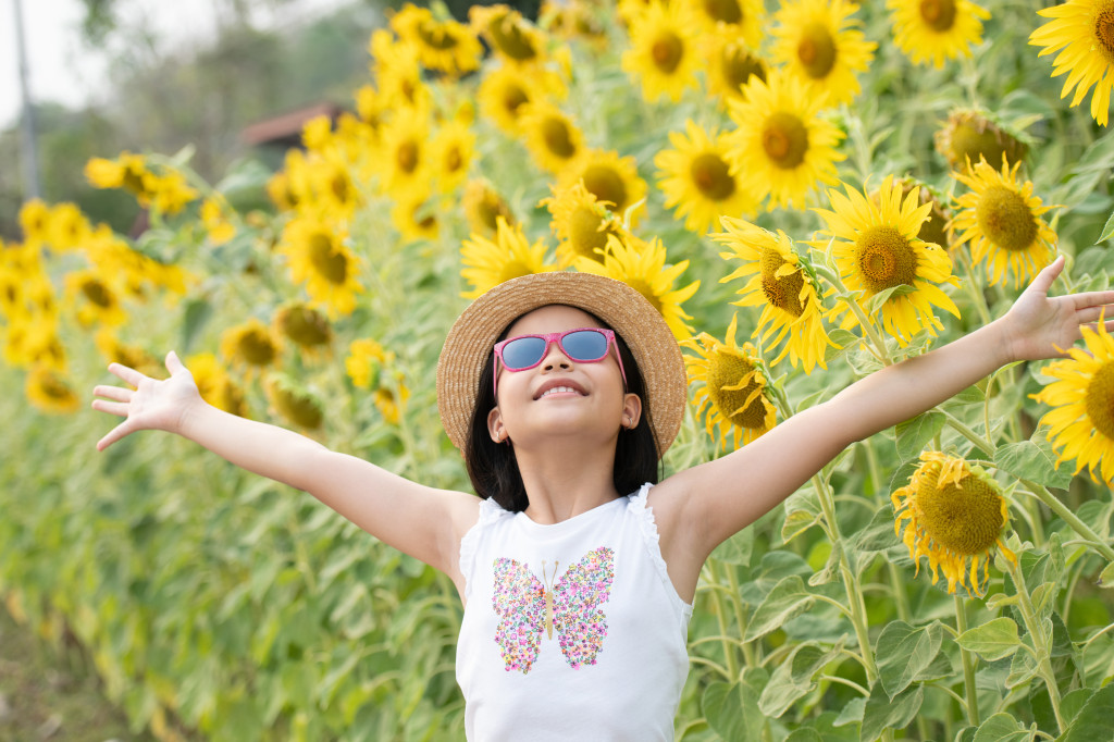 happy little asian girl having fun among blooming sunflowers und