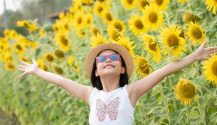 happy little asian girl having fun among blooming sunflowers und