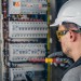 Man, an electrical technician working in a switchboard with fuses.