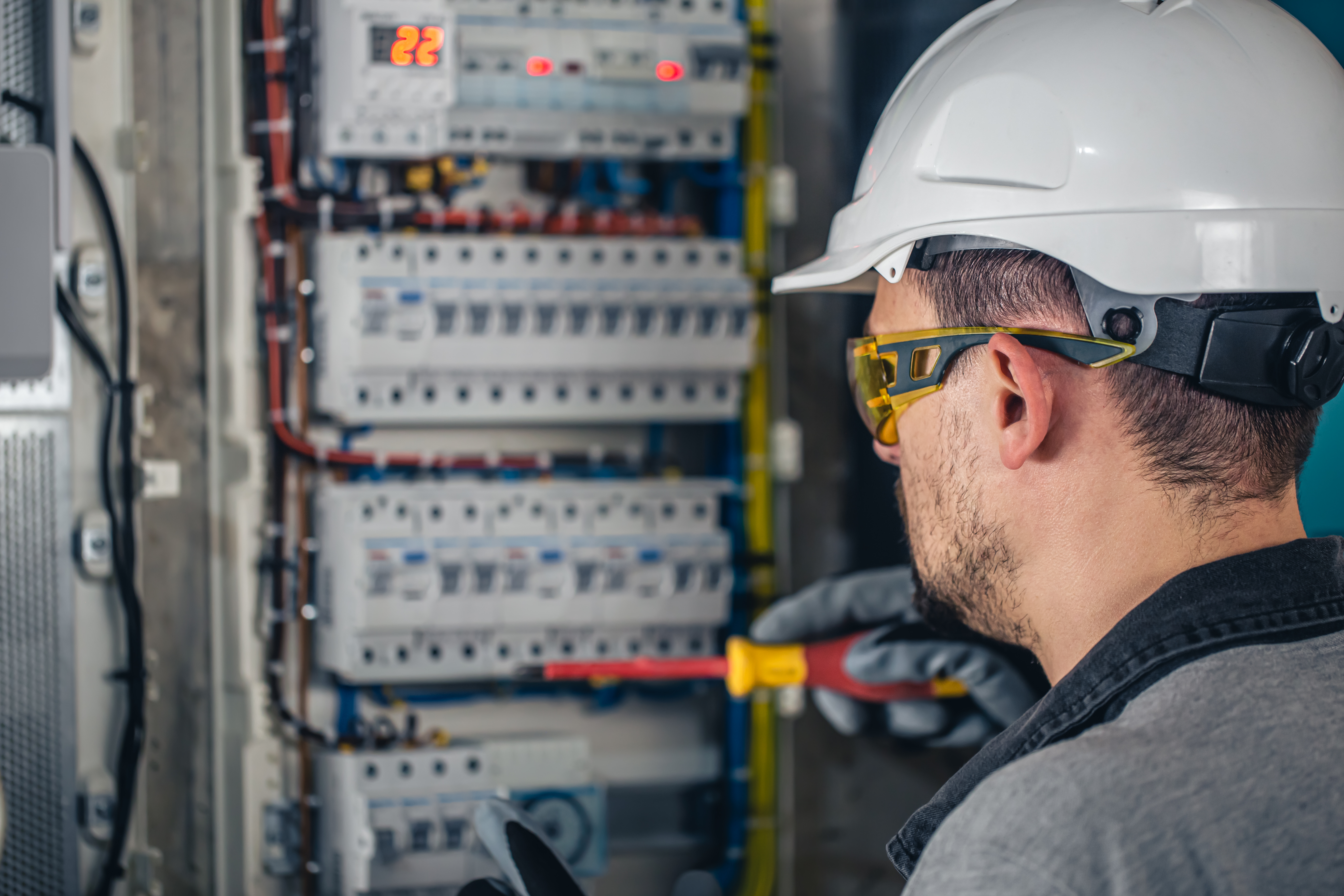 Man, an electrical technician working in a switchboard with fuses.