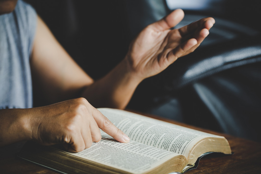 Spirituality and religion, Hands folded in prayer on a Holy Bibl