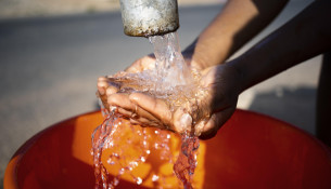 african-woman-pouring-water-recipient-outdoors