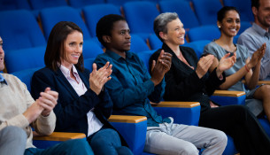 Business executives applauding in a business meeting at conference center