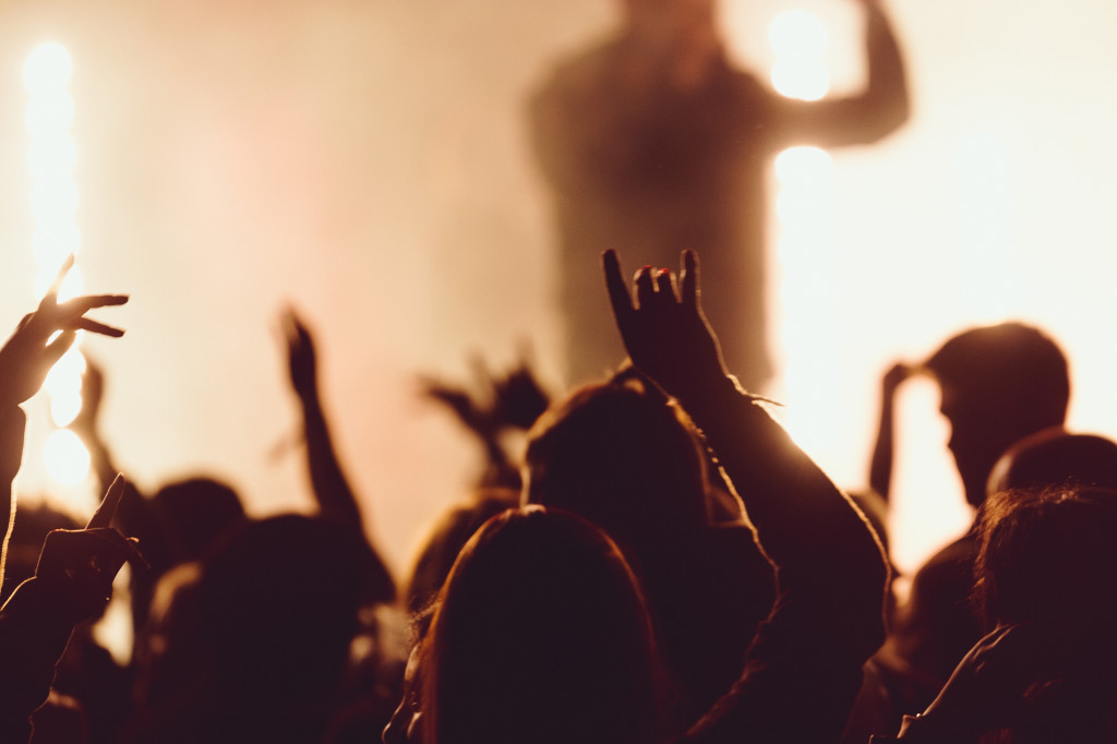 Dancing at a concert while the singer is performing surrounded with lights