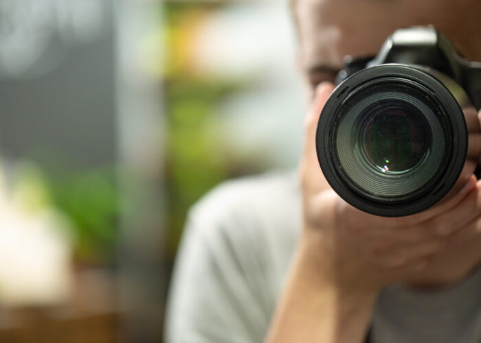 Reflection in the mirror of a man with a camera copy space.